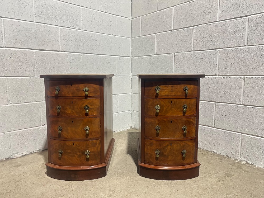 A pair of 19th-century mahogany bedside chests with curved bowfront drawers and ornamental brass drop handles. View II