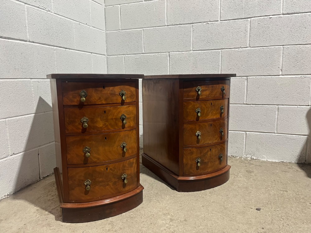 A pair of 19th-century mahogany bedside chests with curved bowfront drawers and ornamental brass drop handles. View V