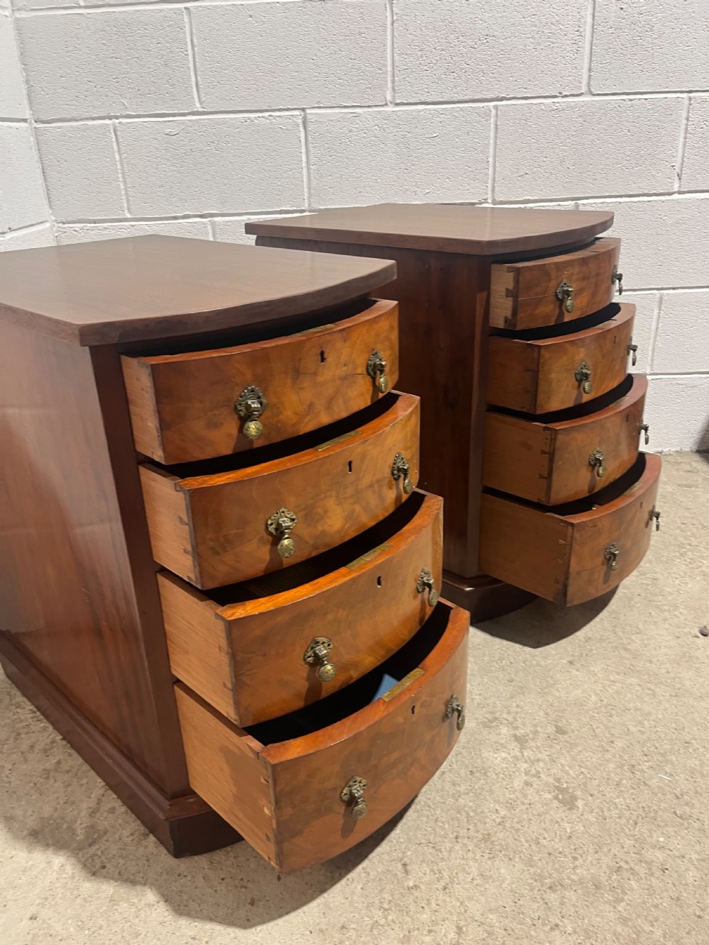 A pair of 19th-century mahogany bedside chests with curved bowfront drawers and ornamental brass drop handles. View X