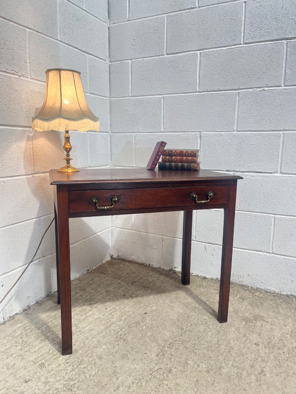 An early nineteenth-century dark oak side table featuring a single frieze drawer with brass drop handles and straight square legs. View II