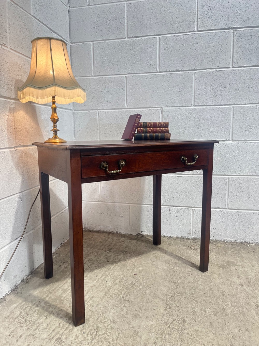 An early nineteenth-century dark oak side table featuring a single frieze drawer with brass drop handles and straight square legs. View III