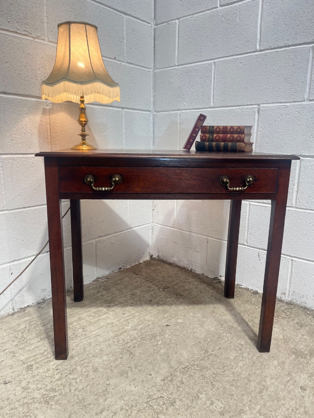 An early nineteenth-century dark oak side table featuring a single frieze drawer with brass drop handles and straight square legs. View IV