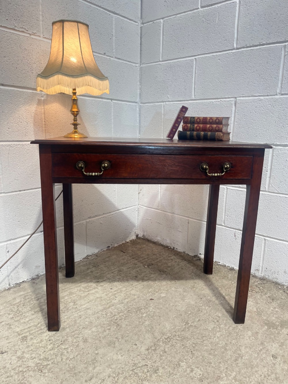 An early nineteenth-century dark oak side table featuring a single frieze drawer with brass drop handles and straight square legs. View V