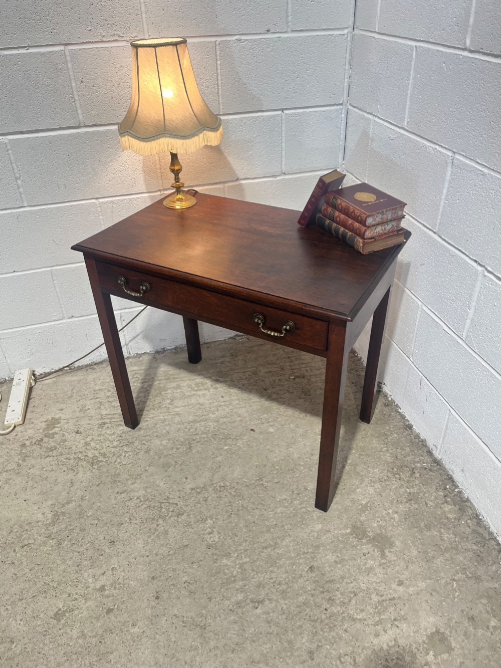 An early nineteenth-century dark oak side table featuring a single frieze drawer with brass drop handles and straight square legs. View VI