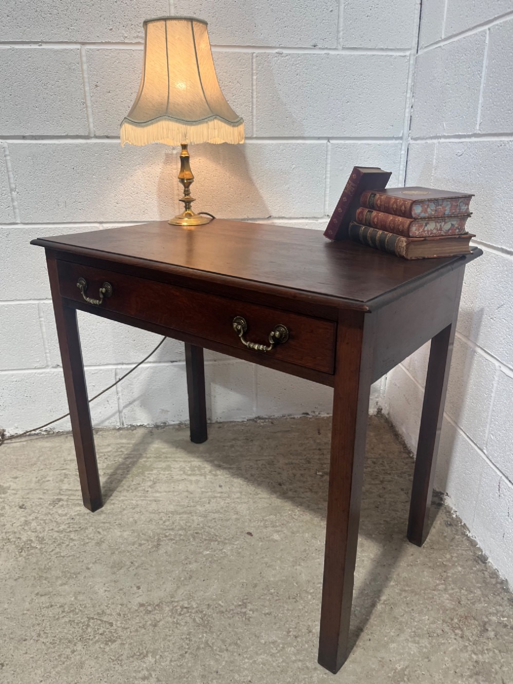 An early nineteenth-century dark oak side table featuring a single frieze drawer with brass drop handles and straight square legs. View VII