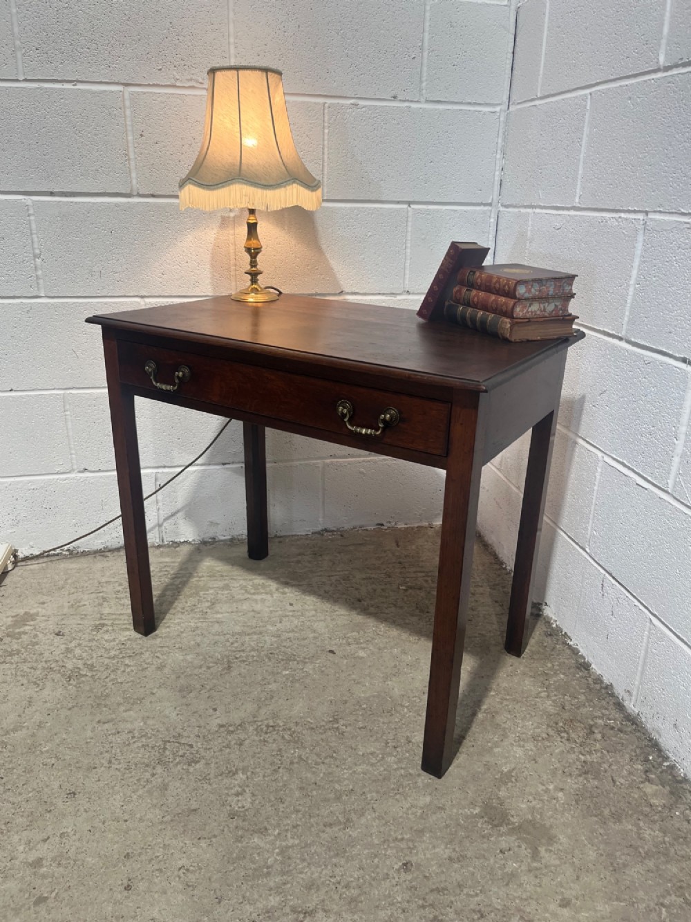 An early nineteenth-century dark oak side table featuring a single frieze drawer with brass drop handles and straight square legs. View VIII