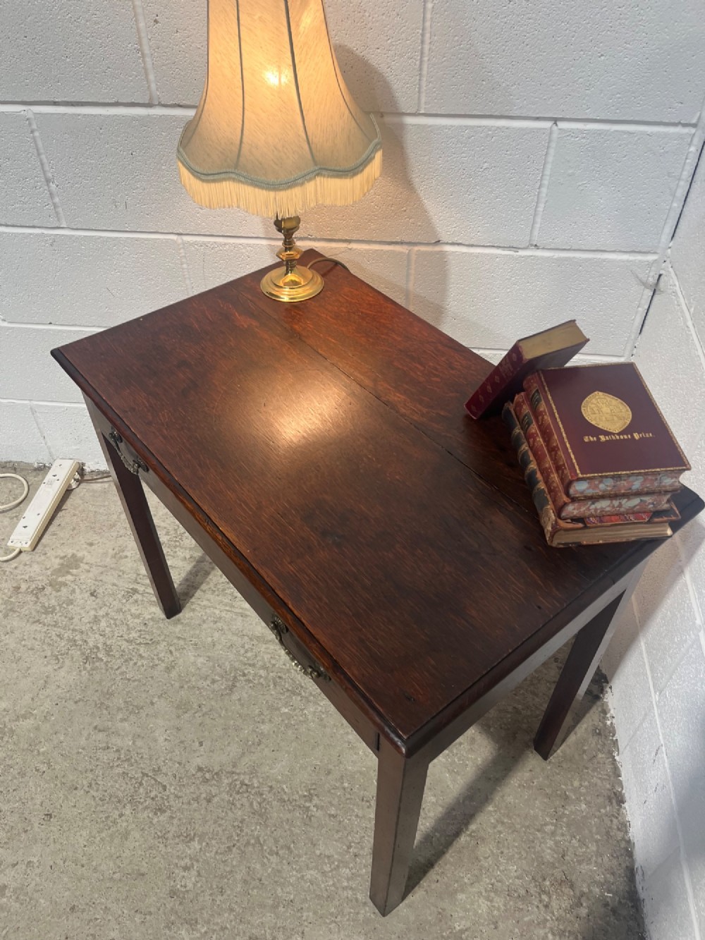 An early nineteenth-century dark oak side table featuring a single frieze drawer with brass drop handles and straight square legs. View IX