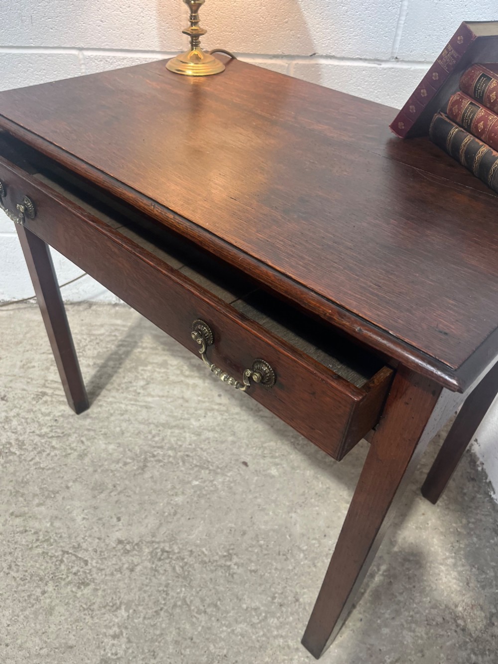 An early nineteenth-century dark oak side table featuring a single frieze drawer with brass drop handles and straight square legs. View XI