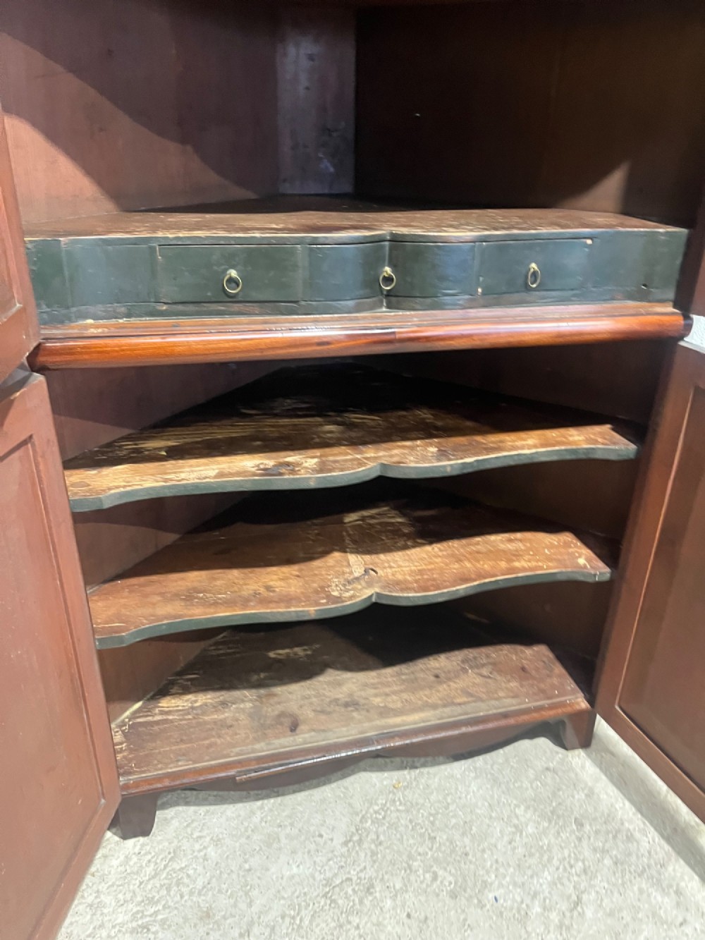 A tall Georgian floor-standing corner cupboard crafted from dark flame mahogany with upper and lower double-panelled doors and brass escutcheons. View X