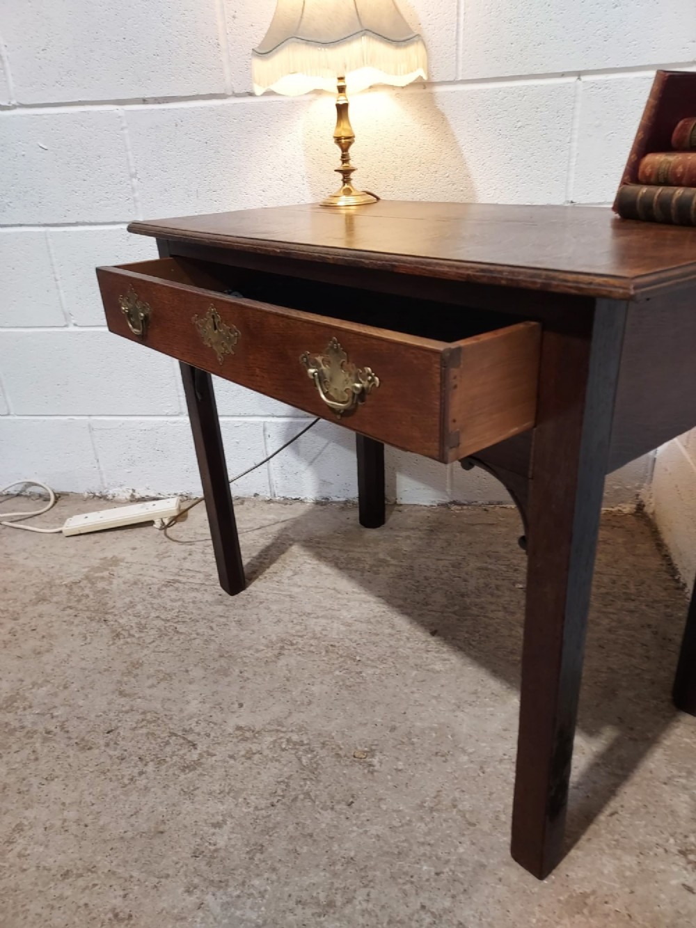 An early 19th-century rectangular oak side table with a single drawer featuring brass handles, a keyhole escutcheon, corner spandrel brackets, and four straight legs. View II