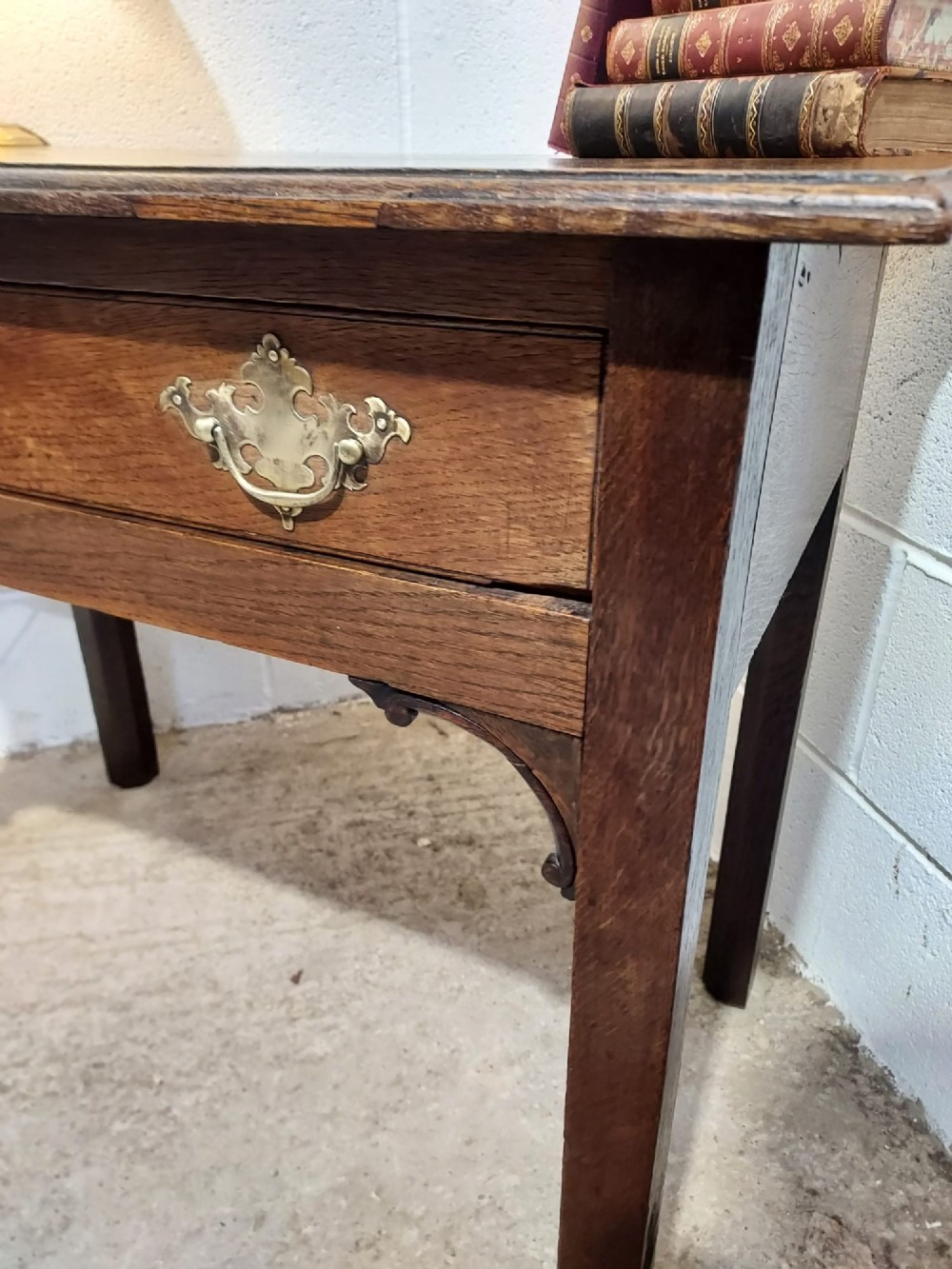 An early 19th-century rectangular oak side table with a single drawer featuring brass handles, a keyhole escutcheon, corner spandrel brackets, and four straight legs. View III