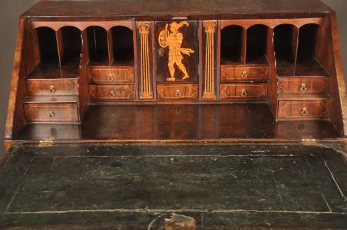 fig 1. An early 18th-century Irish walnut slant-front bureau featuring engraved brass drop handles, keyhole escutcheons, and bracket feet.