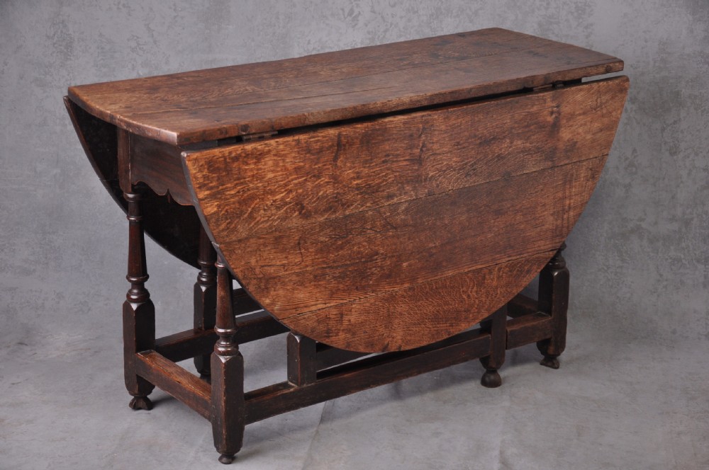 A late seventeenth-century oak gateleg dining table featuring an oval top, turned legs, drop leaves, and a stretcher base. View II
