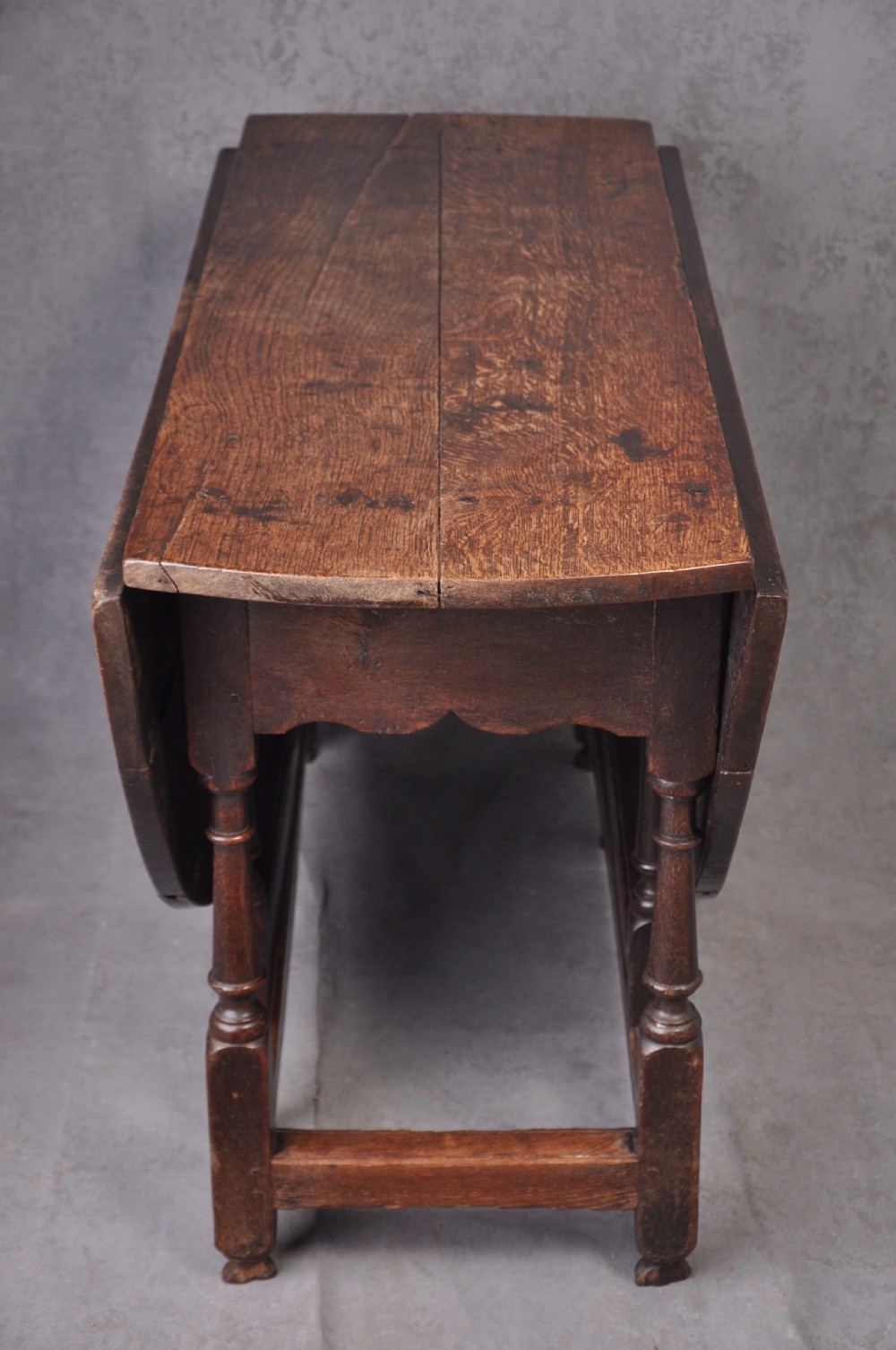 A late seventeenth-century oak gateleg dining table featuring an oval top, turned legs, drop leaves, and a stretcher base. View III