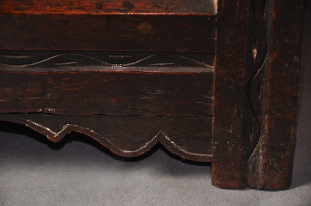A dark oak 17th-century carved coffer featuring three front panels with a central thistle motif and lunette carvings along the upper rail. View III