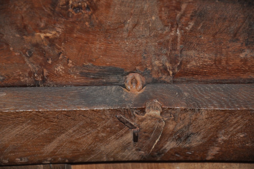 A dark oak 17th-century carved coffer featuring three front panels with a central thistle motif and lunette carvings along the upper rail. View VI