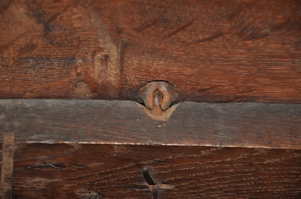 A dark oak 17th-century carved coffer featuring three front panels with a central thistle motif and lunette carvings along the upper rail. View VII