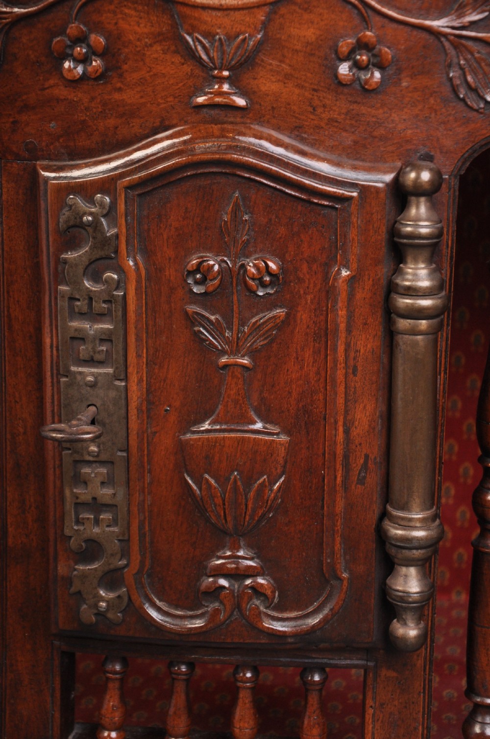 An 18th-century carved walnut French panettiere featuring turned wooden spindles, a central door with carved urn motifs, top finials, and short cabriole legs. View II