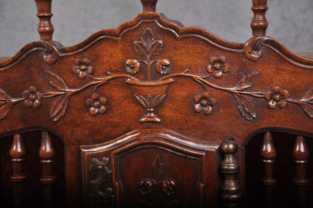 An 18th-century carved walnut French panettiere featuring turned wooden spindles, a central door with carved urn motifs, top finials, and short cabriole legs. View III