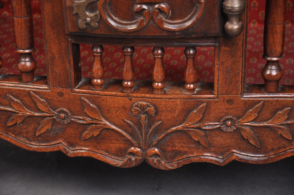 An 18th-century carved walnut French panettiere featuring turned wooden spindles, a central door with carved urn motifs, top finials, and short cabriole legs. View IV