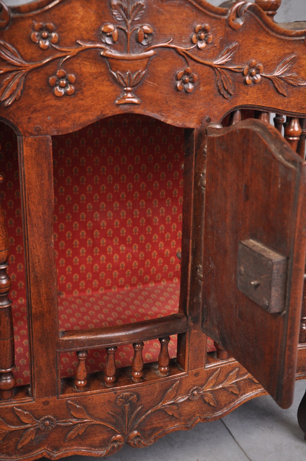 An 18th-century carved walnut French panettiere featuring turned wooden spindles, a central door with carved urn motifs, top finials, and short cabriole legs. View VI