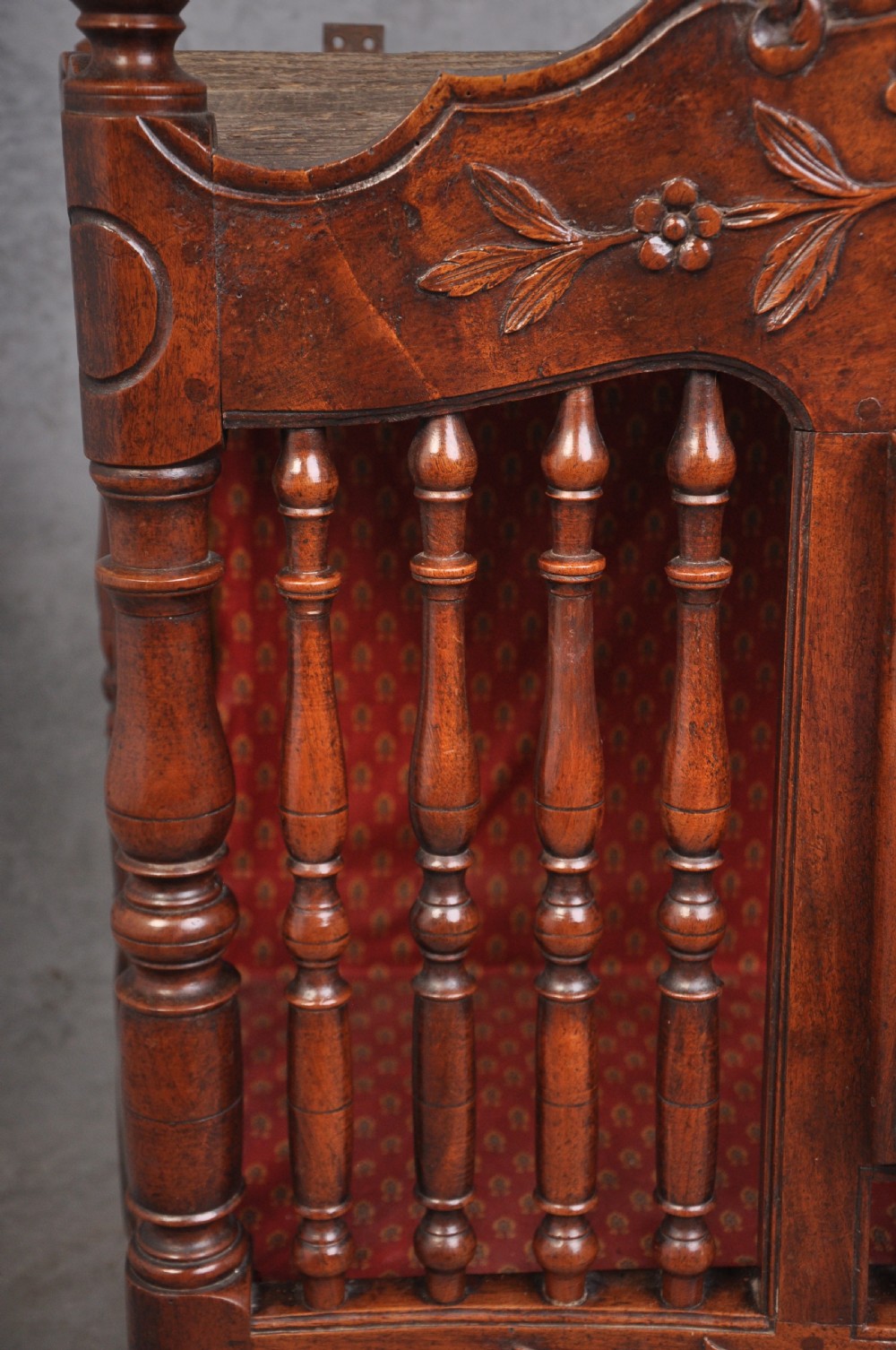 An 18th-century carved walnut French panettiere featuring turned wooden spindles, a central door with carved urn motifs, top finials, and short cabriole legs. View IX