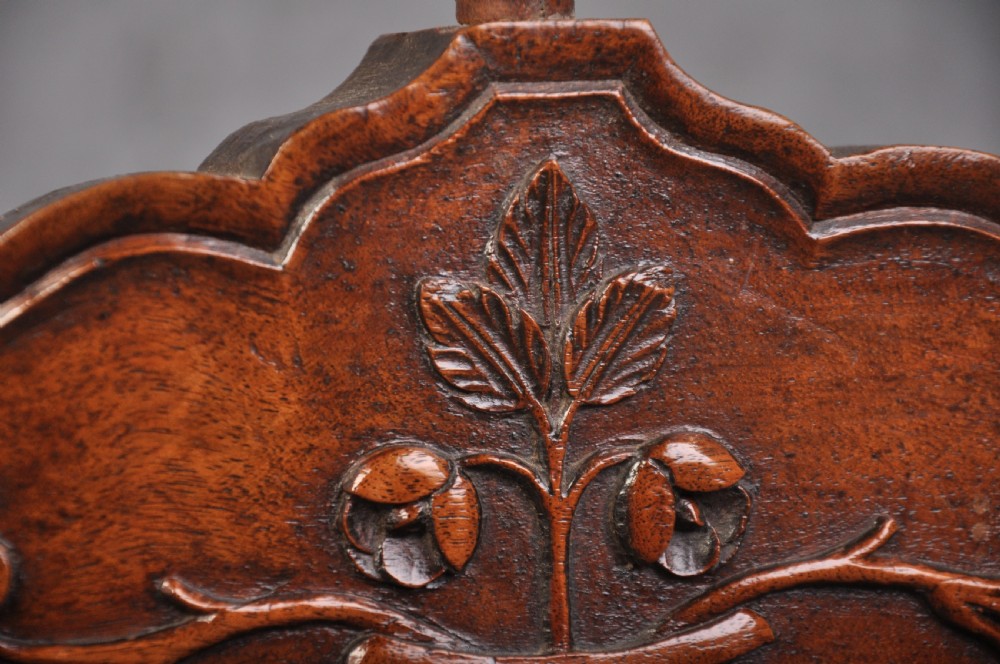 An 18th-century carved walnut French panettiere featuring turned wooden spindles, a central door with carved urn motifs, top finials, and short cabriole legs. View X