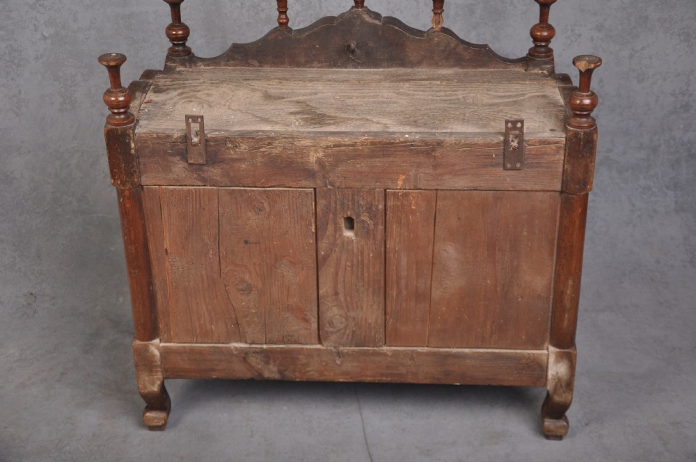 An 18th-century carved walnut French panettiere featuring turned wooden spindles, a central door with carved urn motifs, top finials, and short cabriole legs. View XII