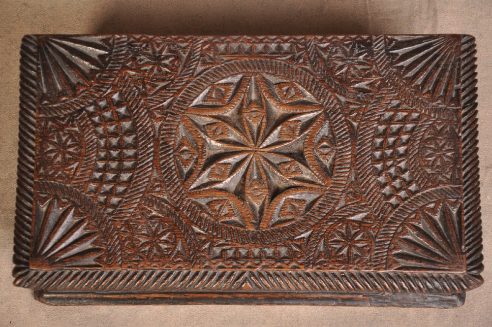 A rectangular dark oak box with geometric star chip carvings across the lid and front face, featuring a central iron keyhole. View II