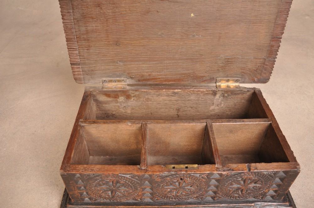 A rectangular dark oak box with geometric star chip carvings across the lid and front face, featuring a central iron keyhole. View VI