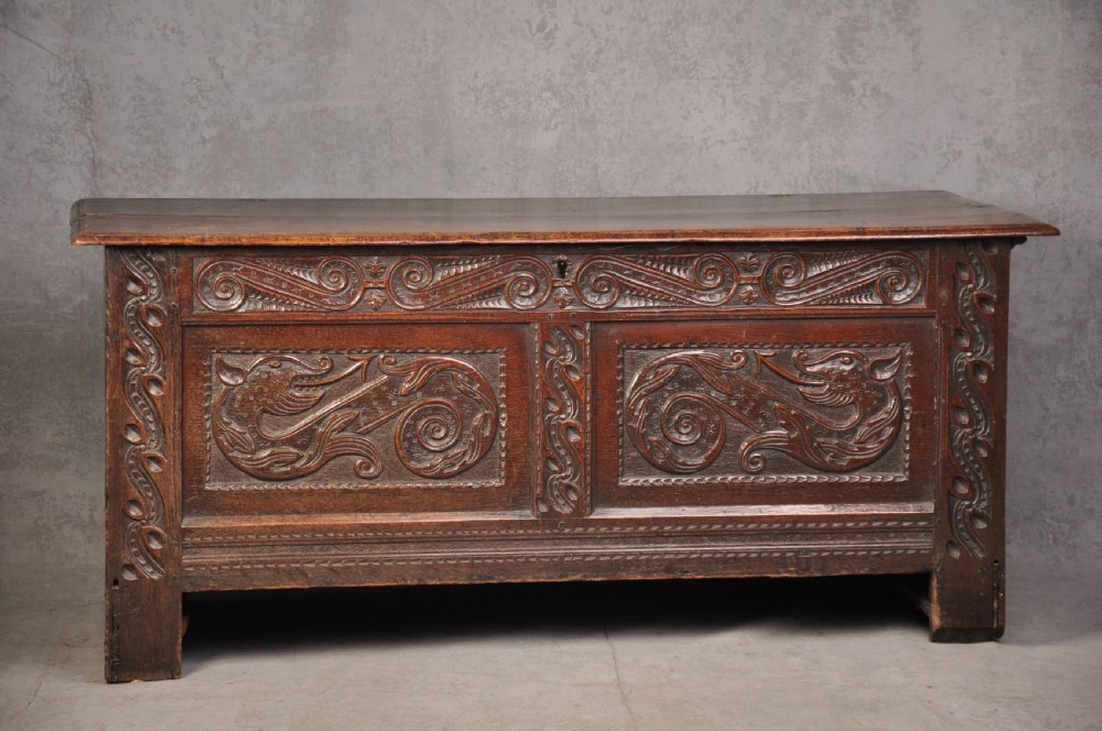 A 17th-century carved oak coffer featuring relief-carved front panels and a dark aged patina.