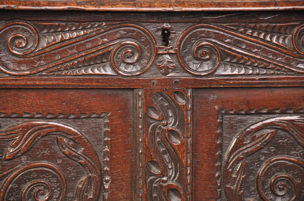 A 17th-century carved oak coffer featuring relief-carved front panels and a dark aged patina. View III