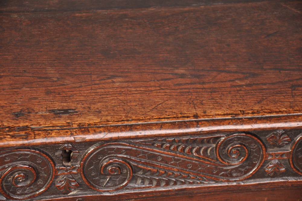 A 17th-century carved oak coffer featuring relief-carved front panels and a dark aged patina. View V