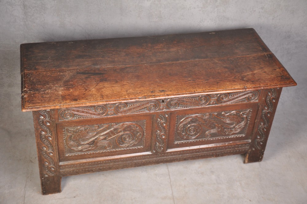A 17th-century carved oak coffer featuring relief-carved front panels and a dark aged patina. View VI
