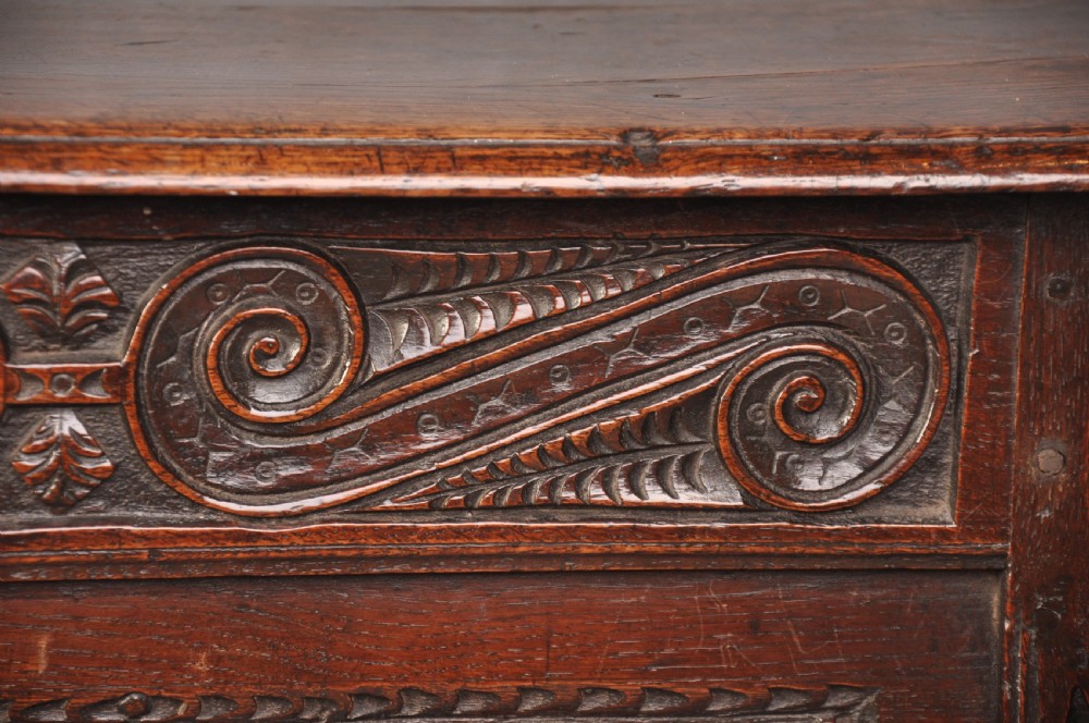 A 17th-century carved oak coffer featuring relief-carved front panels and a dark aged patina. View VII