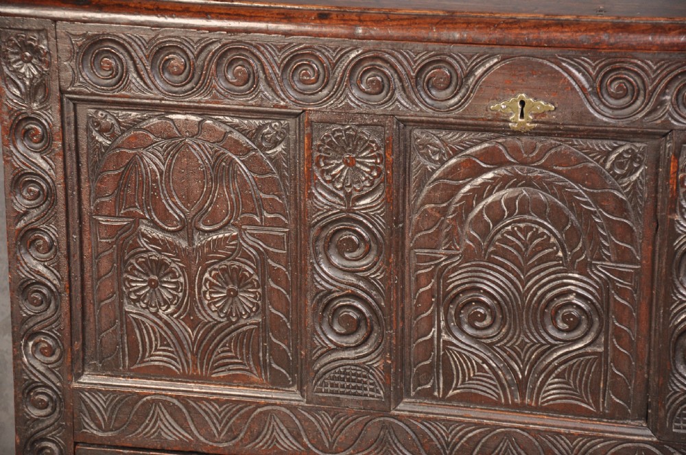A seventeenth-century carved dark oak Yorkshire coffer featuring three arcaded floral panels, scrollwork friezes, two lower drawers, and brass keyhole escutcheons. View III