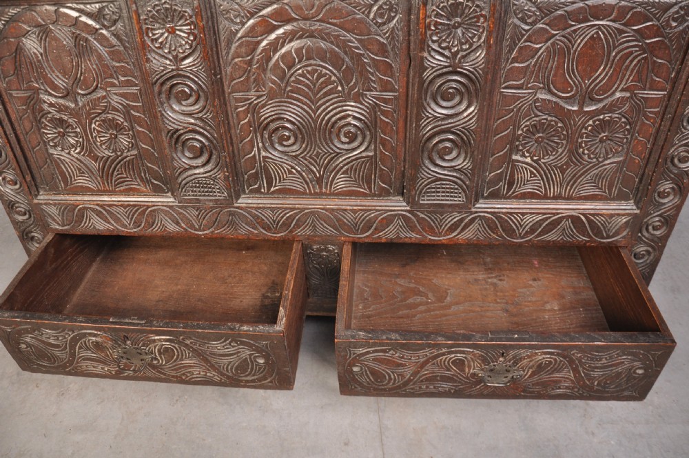 A seventeenth-century carved dark oak Yorkshire coffer featuring three arcaded floral panels, scrollwork friezes, two lower drawers, and brass keyhole escutcheons. View IV