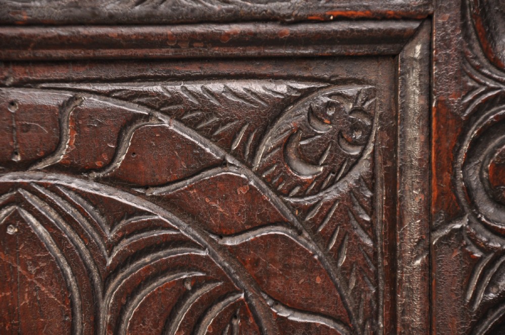 A seventeenth-century carved dark oak Yorkshire coffer featuring three arcaded floral panels, scrollwork friezes, two lower drawers, and brass keyhole escutcheons. View V