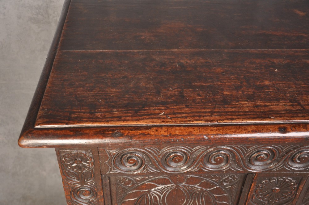 A seventeenth-century carved dark oak Yorkshire coffer featuring three arcaded floral panels, scrollwork friezes, two lower drawers, and brass keyhole escutcheons. View VII