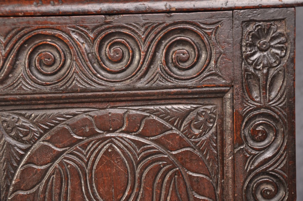 A seventeenth-century carved dark oak Yorkshire coffer featuring three arcaded floral panels, scrollwork friezes, two lower drawers, and brass keyhole escutcheons. View XI