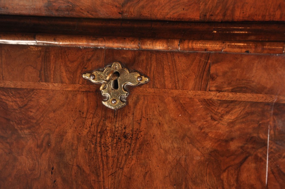 An early 18th-century walnut bureau bookcase with a double-domed top, turned finials, two arched mirrored doors, a slant-front writing slope, and drawers on bracket feet. View VIII