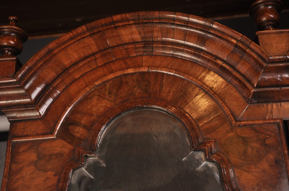 An early 18th-century walnut bureau bookcase with a double-domed top, turned finials, two arched mirrored doors, a slant-front writing slope, and drawers on bracket feet. View IX