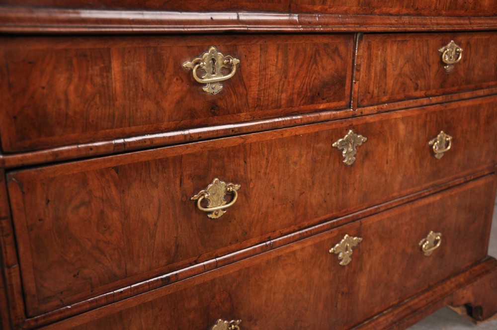 An early 18th-century walnut bureau bookcase with a double-domed top, turned finials, two arched mirrored doors, a slant-front writing slope, and drawers on bracket feet. View X