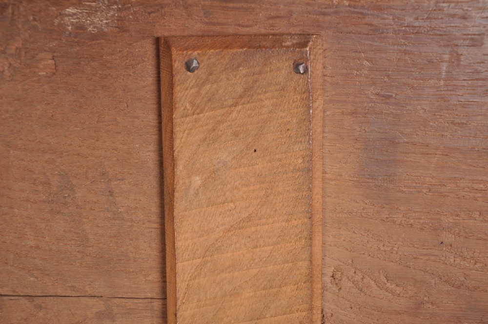 A dark brown 17th century carved oak coffer featuring three carved front panels with foliate motifs and an iron lock plate. View VIII