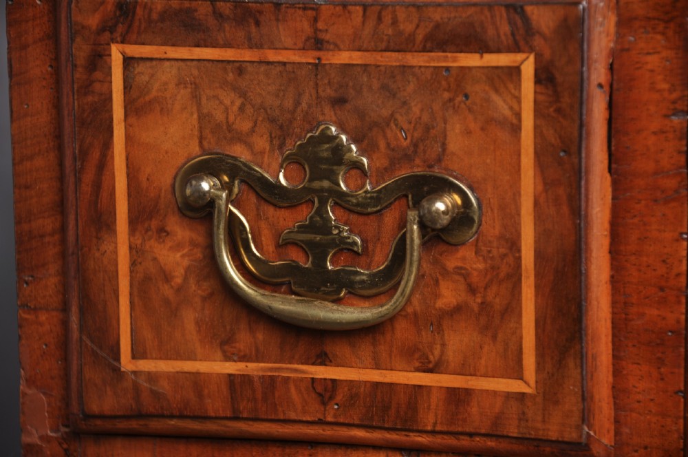 An early 18th-century walnut kneehole desk featuring crossbanded drawer fronts, brass handles, a central recessed cupboard, and bracket feet. View III
