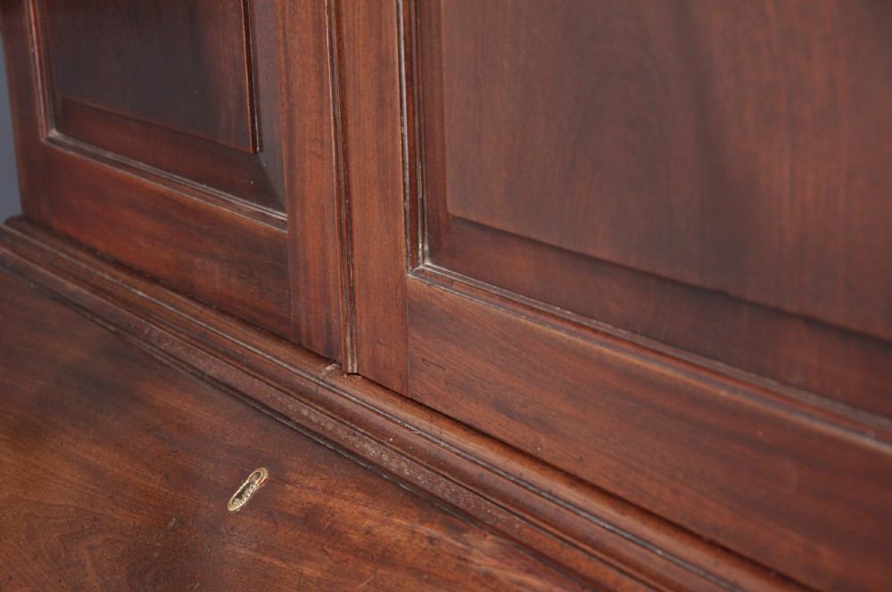 An 18th-century mahogany bureau bookcase featuring a blind two-door upper cabinet, a slant-front writing slope, four long drawers, and bracket feet. View XIII