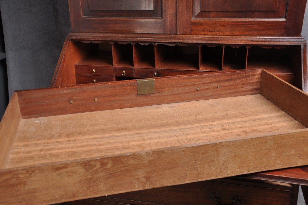 An 18th-century mahogany bureau bookcase featuring a blind two-door upper cabinet, a slant-front writing slope, four long drawers, and bracket feet. View XVI
