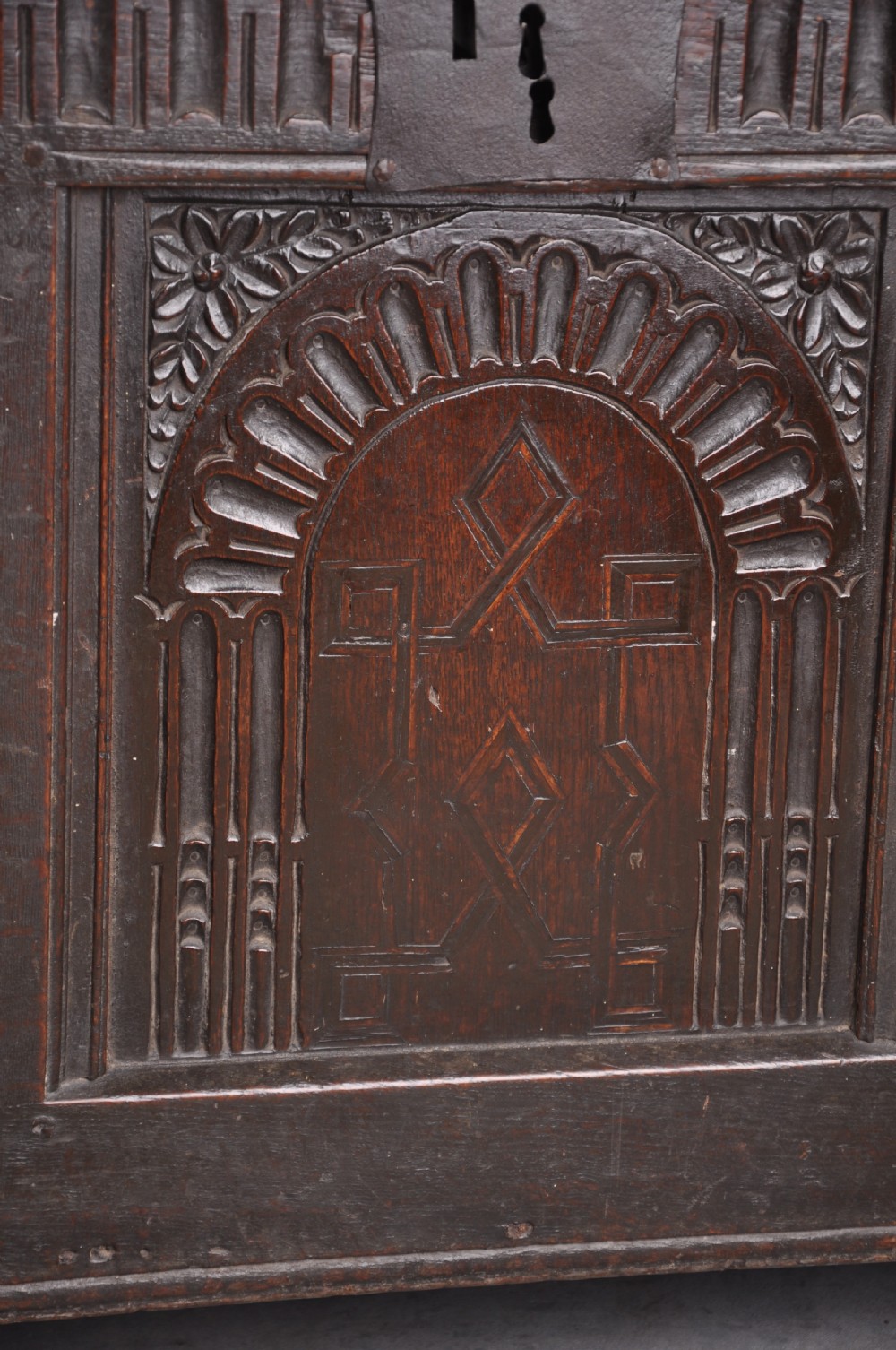 A dark oak three-panel coffer featuring relief-carved arches, geometric strapwork, a carved frieze, and a central iron keyhole plate. View III