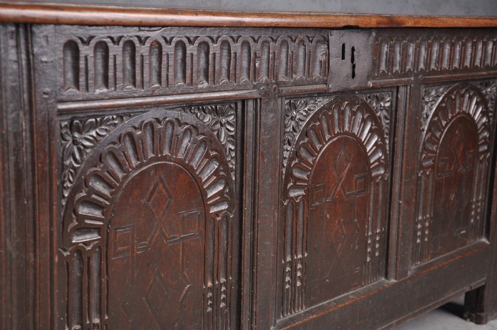 A dark oak three-panel coffer featuring relief-carved arches, geometric strapwork, a carved frieze, and a central iron keyhole plate. View V