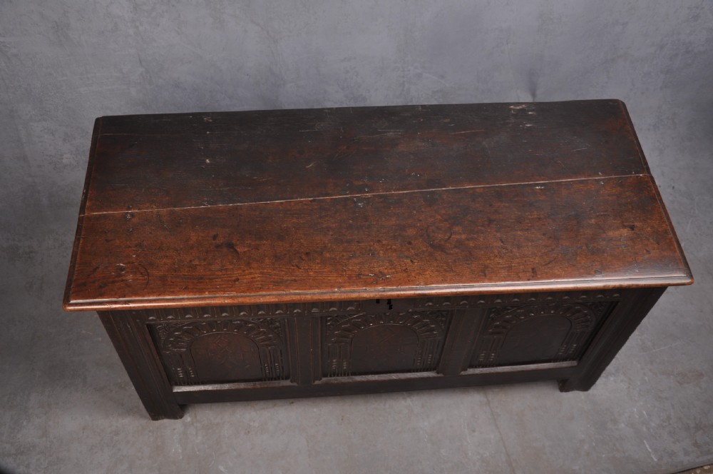 A dark oak three-panel coffer featuring relief-carved arches, geometric strapwork, a carved frieze, and a central iron keyhole plate. View VI
